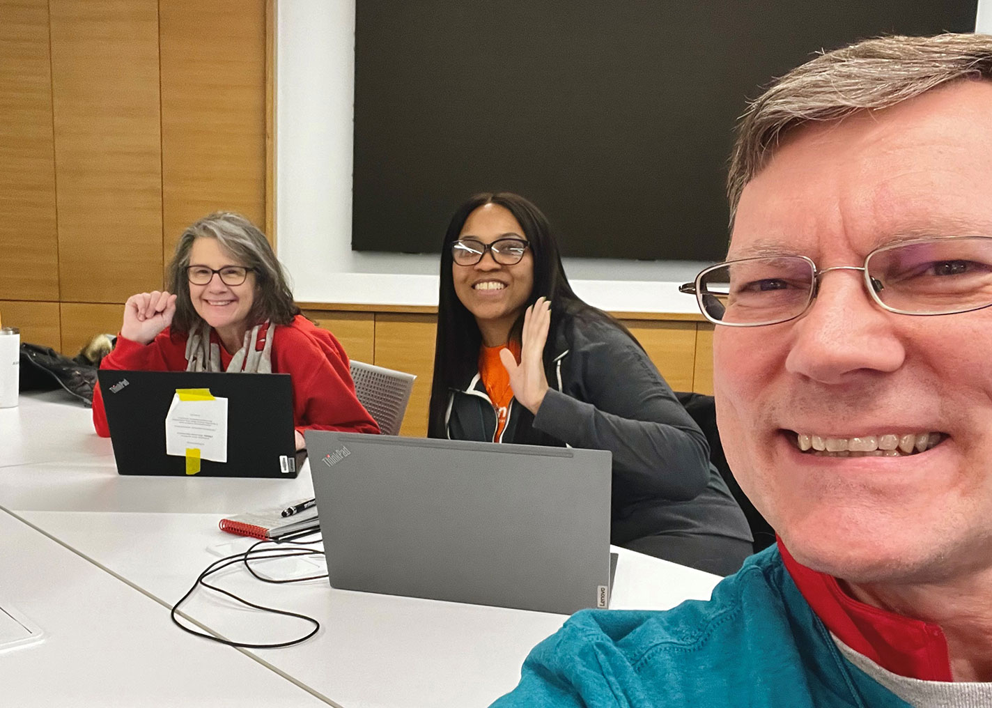 Several Ascendium employees smile at the camera as they review essays as volunteers.