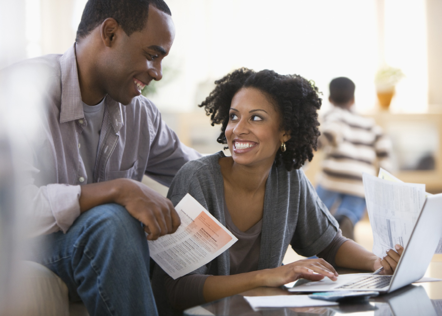 A smiling couple looks over their student loan finances at home.