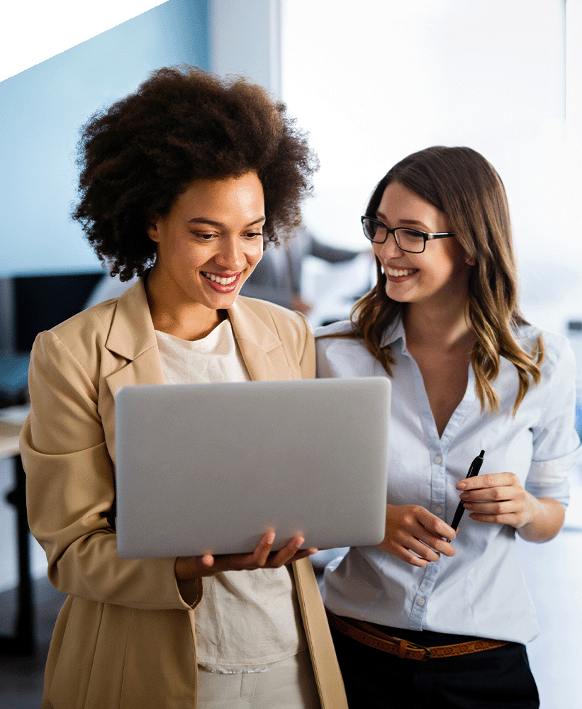 Two smiling employees looking at a laptop together.