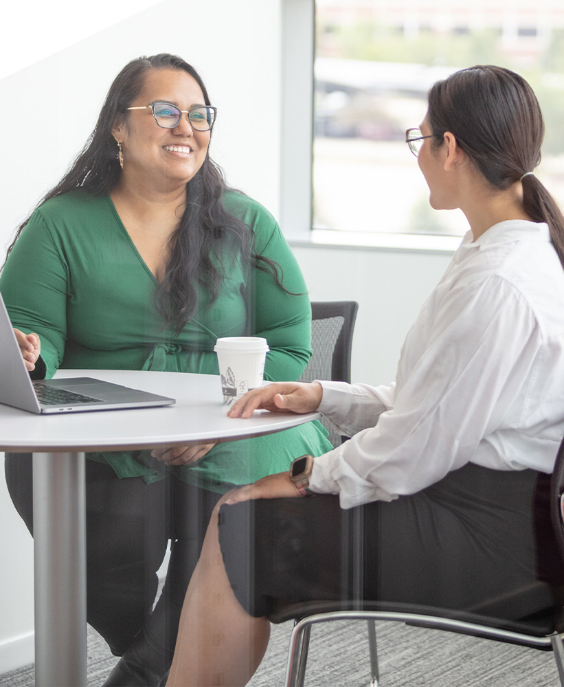 Two people sitting at a confernce table having a discussion. 