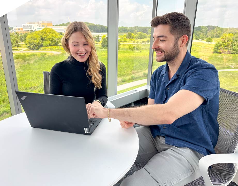 An intern and a mentor working at a laptop. 