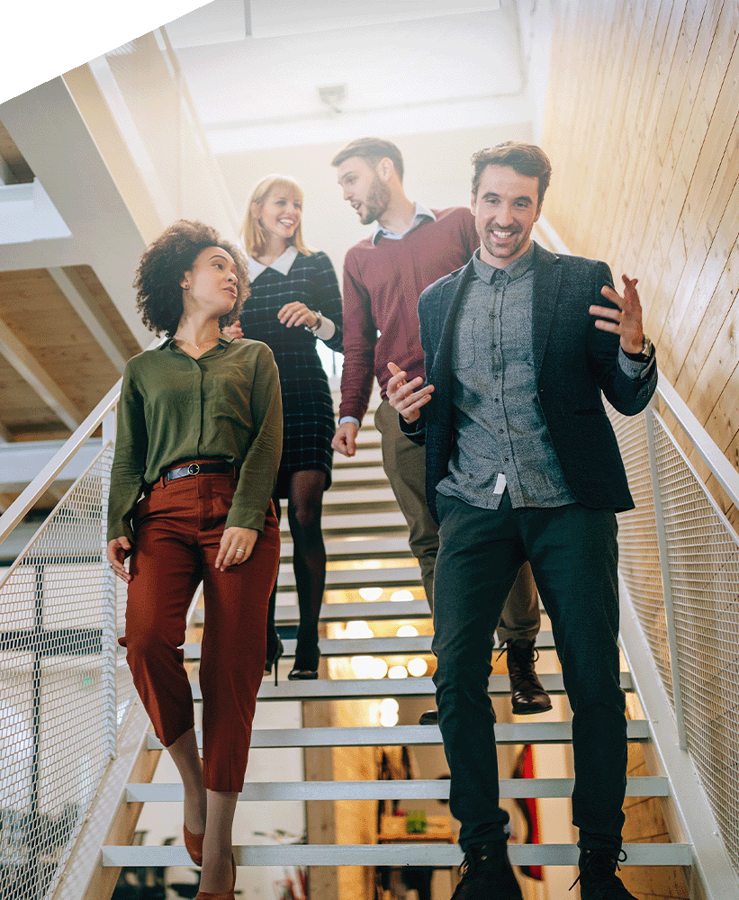 A group of employees discussing work as they walk down stairs.