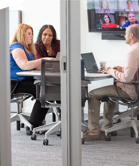 Three employees working diligently in a meeting.