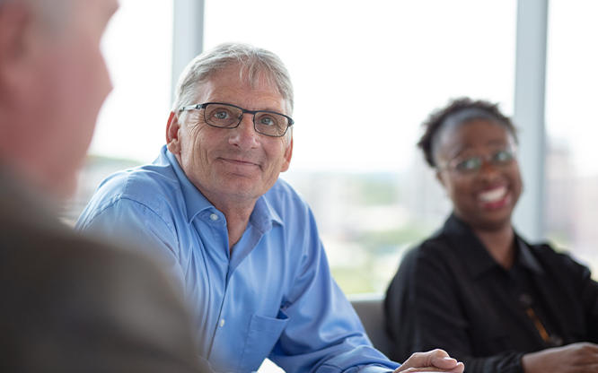 Ascendium employees conversing in a board room.